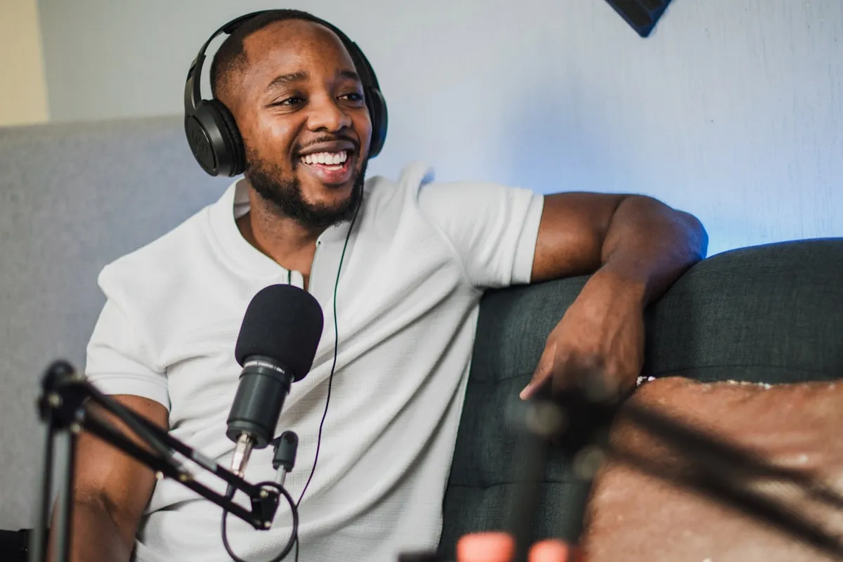 Radio host speaking into a professional microphone with warm studio lighting, representing the human connection and personality that AI enhances but never replaces in broadcasting