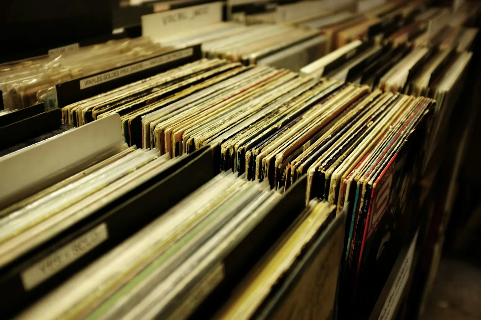 Rows of vintage vinyl records organized in wooden crates at a record store, representing the deep music library that powers Classic Hits radio content