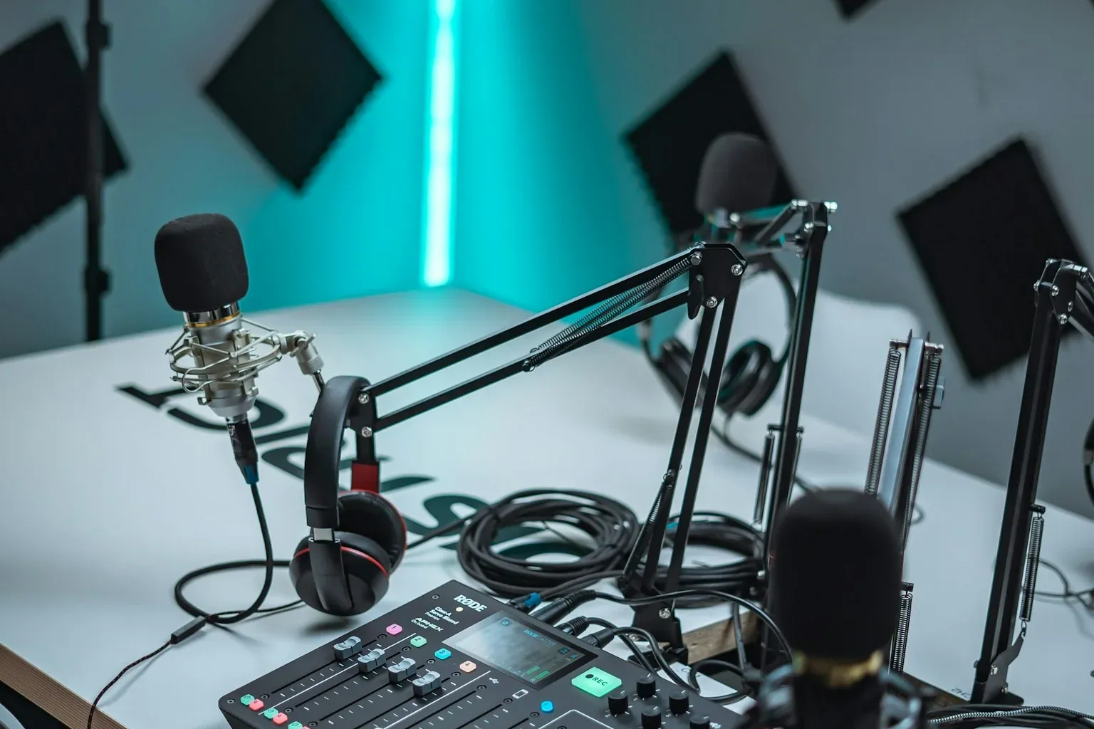 Professional black broadcast microphone and audio mixer console in a radio production studio, editorial quality photograph
