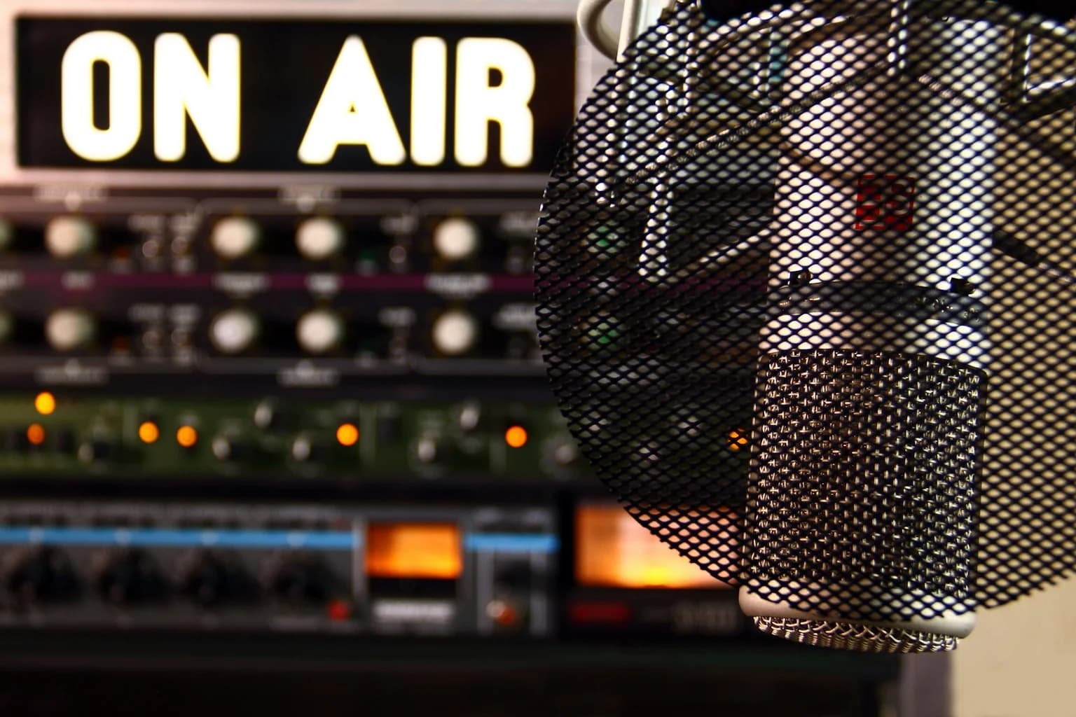 Professional radio studio microphone with ON AIR sign and broadcast equipment in background