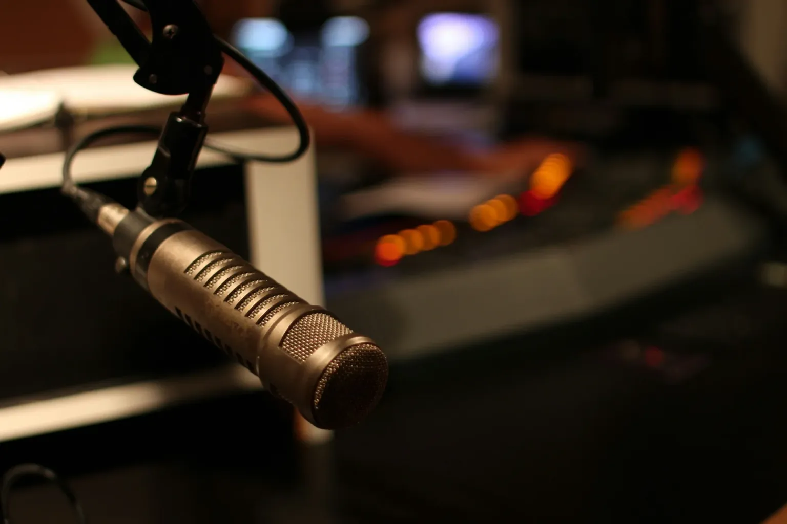 Professional broadcast microphone on stand in radio studio with warm lighting, ready for on-air show