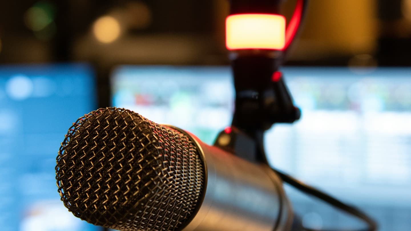A professional studio microphone in front of a computer monitor