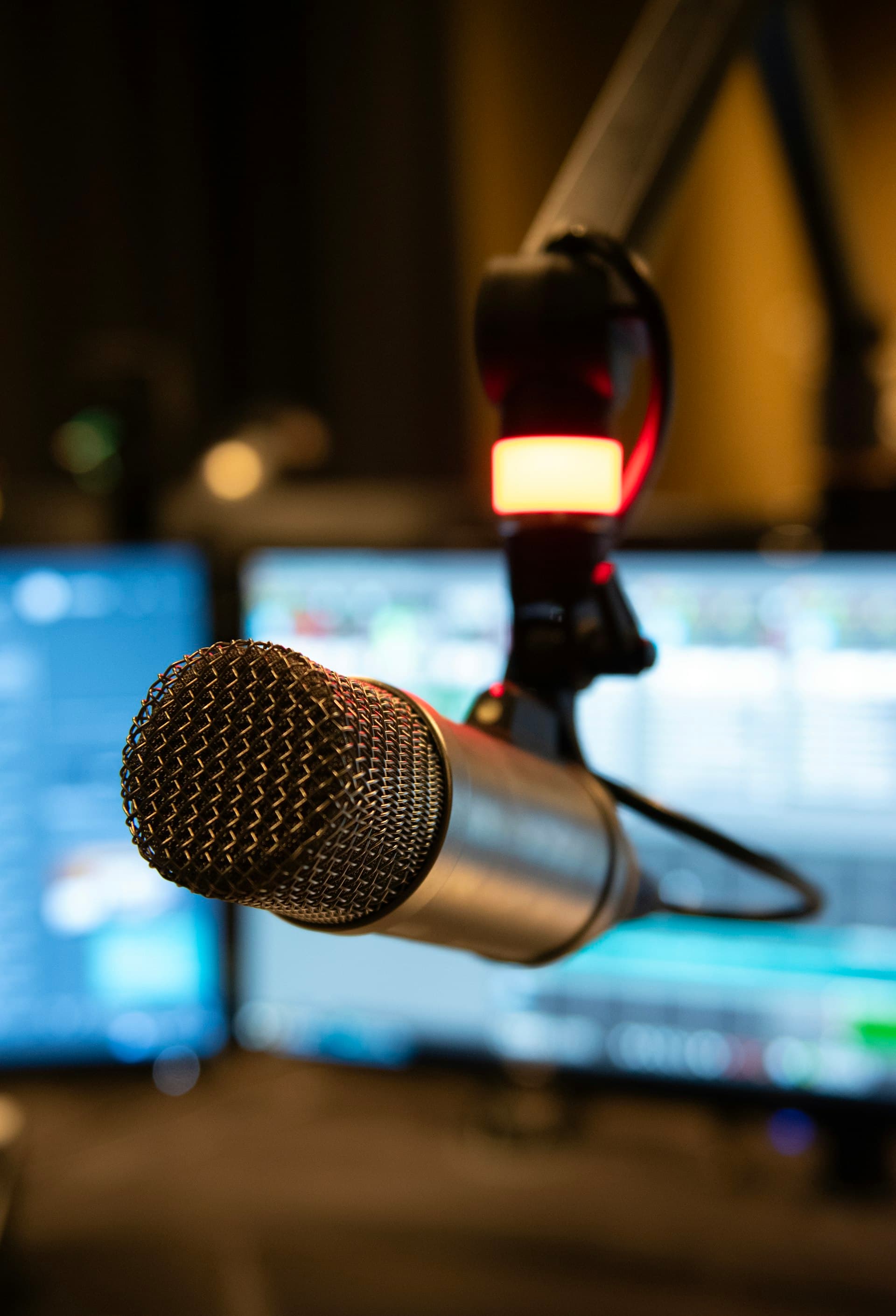 A studio microphone in front of a laptop — modern show prep workspace